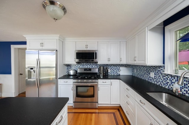 29 Wituwamat Rd, Weymouth, MA 02191 - kitchen with appliances with stainless steel finishes, a sink, dark countertops, white cabinets, and a wainscoted wall