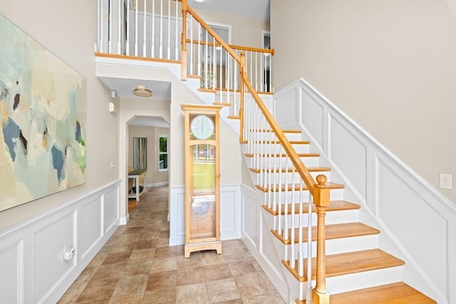 102 Saddleworth Way, Middleboro, MA 02346 - stairway featuring a decorative wall, arched walkways, wainscoting, and a towering ceiling