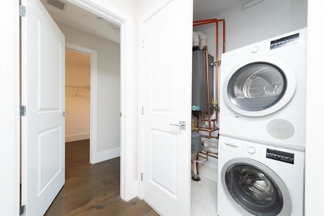 clothes washing area with laundry area, wood finished floors, visible vents, baseboards, and stacked washing maching and dryer