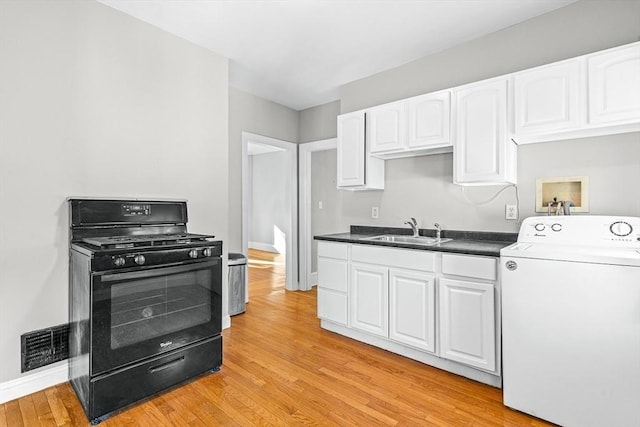 kitchen featuring black gas range, a sink, visible vents, light wood-style floors, and washer / clothes dryer