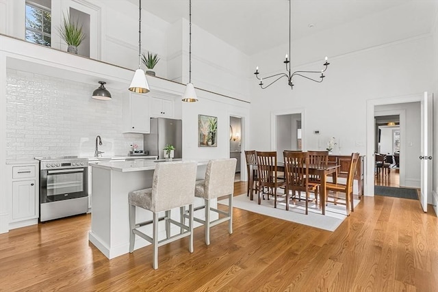 4 Norwood St, Winchester, MA 01890 - kitchen with stainless steel appliances, a breakfast bar area, a center island, light countertops, and light wood-style flooring