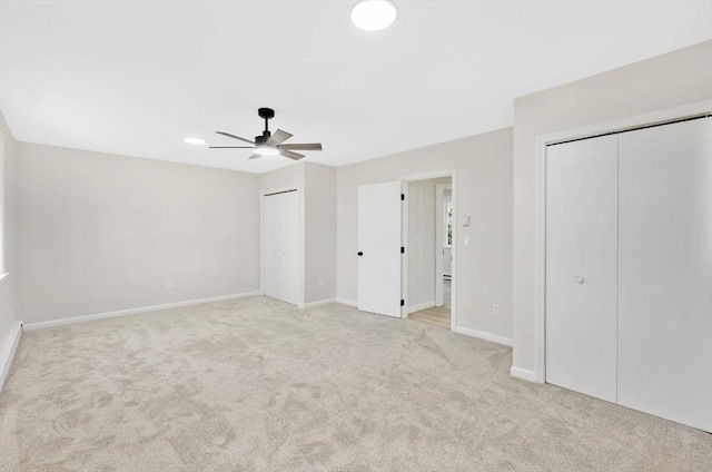 unfurnished bedroom with baseboards, multiple closets, light carpet, recessed lighting, and a ceiling fan