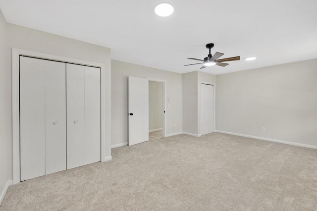 unfurnished bedroom featuring a ceiling fan, light colored carpet, baseboards, and two closets