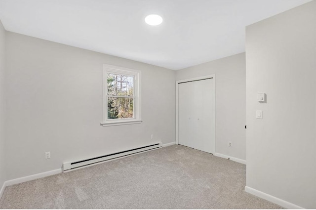 unfurnished bedroom with a closet, baseboards, baseboard heating, and carpet flooring