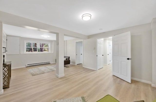 interior space featuring light wood-type flooring, a baseboard heating unit, and baseboards