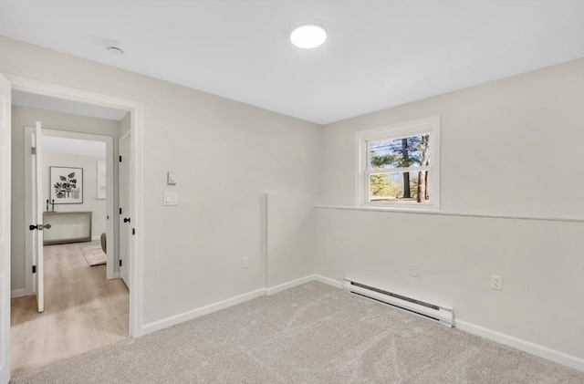 empty room with light carpet, a baseboard heating unit, and baseboards