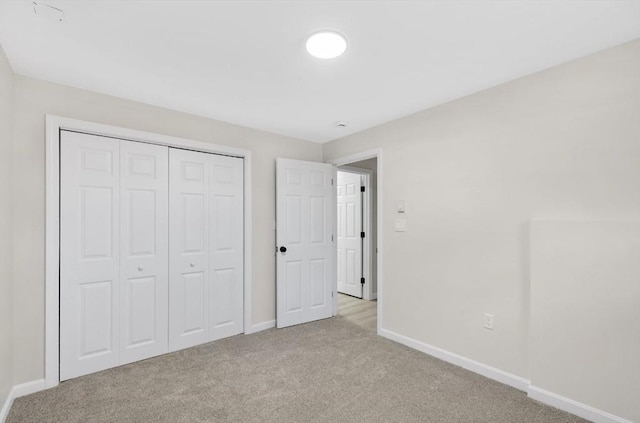 unfurnished bedroom with a closet, baseboards, and carpet flooring