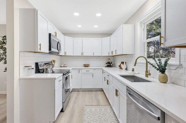 kitchen featuring a sink, light countertops, light wood finished floors, and stainless steel appliances