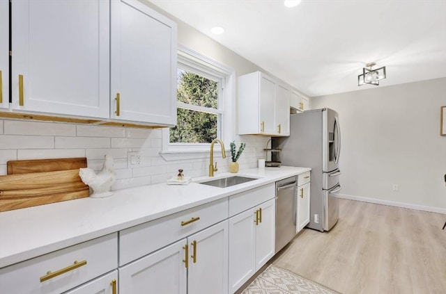 kitchen with a sink, backsplash, stainless steel appliances, white cabinets, and light countertops