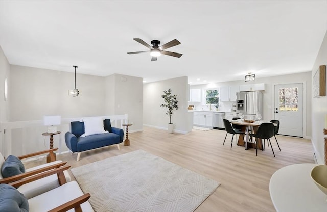 living room featuring ceiling fan, light wood-type flooring, and baseboards