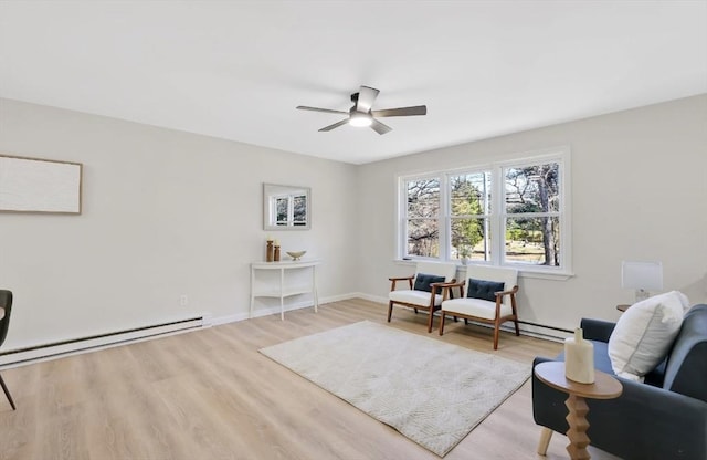 sitting room with light wood-type flooring, a baseboard radiator, baseboards, and ceiling fan