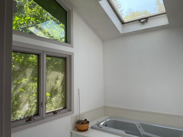 bathroom with vaulted ceiling with skylight, a healthy amount of sunlight, and a tub to relax in