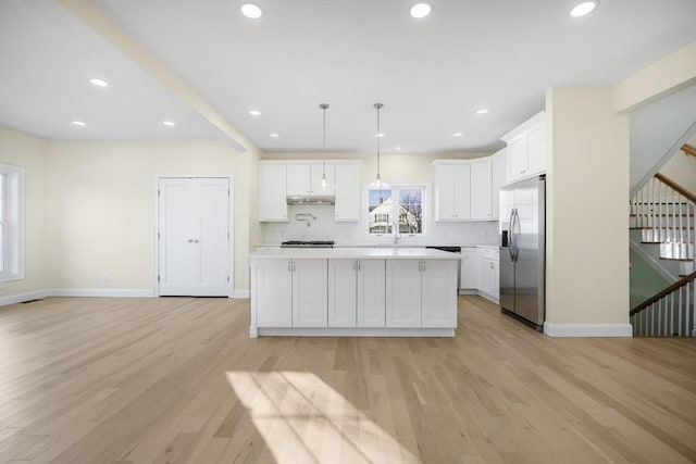 kitchen featuring stainless steel refrigerator with ice dispenser, white cabinetry, light hardwood / wood-style flooring, and hanging light fixtures