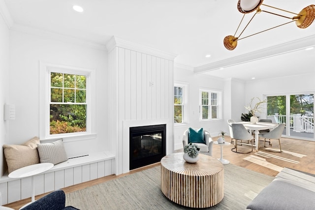 living room with light hardwood / wood-style floors, ornamental molding, and a wealth of natural light