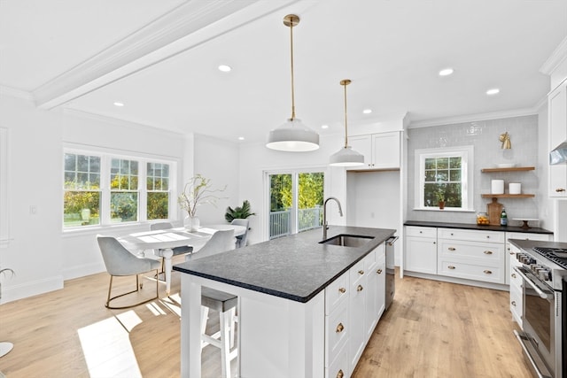 kitchen featuring a center island with sink, white cabinetry, stainless steel appliances, light hardwood / wood-style floors, and sink