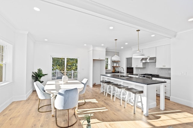 dining room featuring ornamental molding, sink, and light wood-type flooring