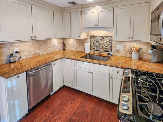 kitchen featuring sink, stainless steel appliances, light stone counters, dark hardwood / wood-style flooring, and decorative backsplash