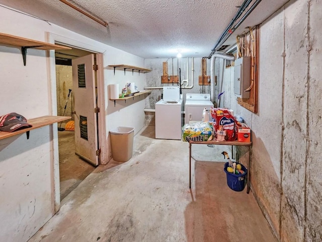 basement with electric panel, washer and dryer, and a textured ceiling