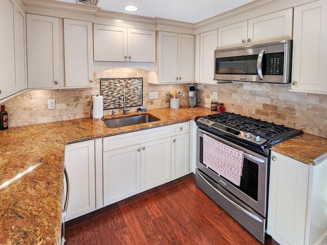 kitchen with stone counters, sink, dark wood-type flooring, tasteful backsplash, and appliances with stainless steel finishes