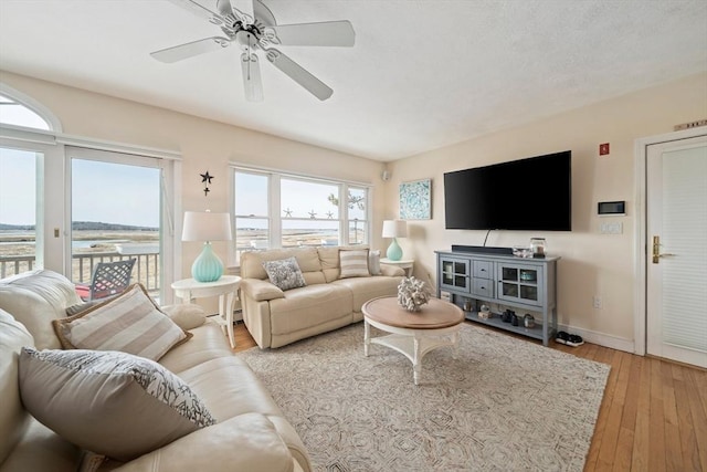 living room featuring ceiling fan, light wood-type flooring, and baseboards