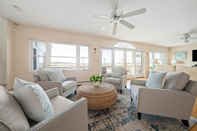 living room with a baseboard heating unit, baseboards, and a ceiling fan