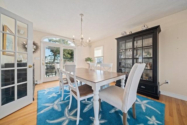 dining area with a chandelier, french doors, baseboards, and wood finished floors