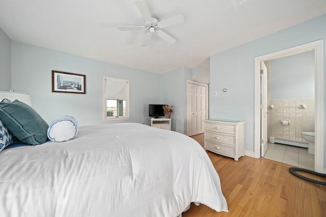 bedroom with a baseboard heating unit, ensuite bath, light wood-style flooring, and a ceiling fan