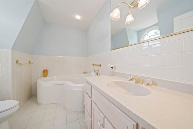 full bath featuring vanity, a garden tub, vaulted ceiling, tile walls, and tile patterned floors