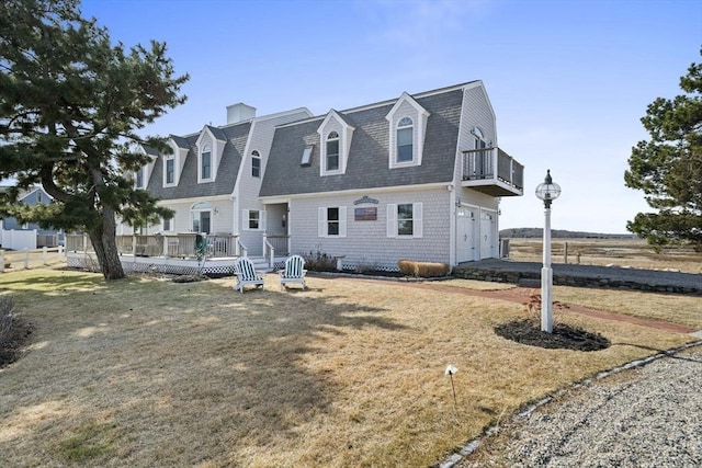 back of house with a gambrel roof, a lawn, a deck, a shingled roof, and a garage