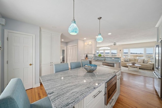 kitchen with a sink, appliances with stainless steel finishes, open floor plan, and white cabinetry