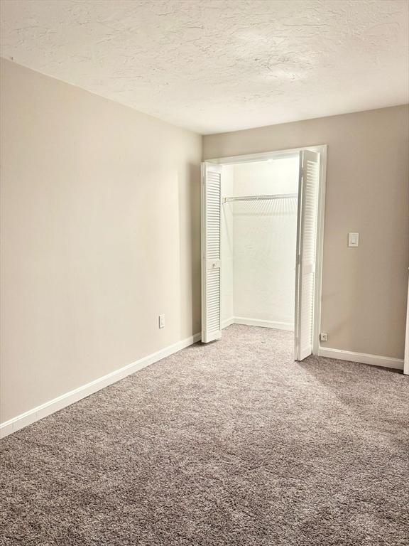 carpeted spare room with a textured ceiling