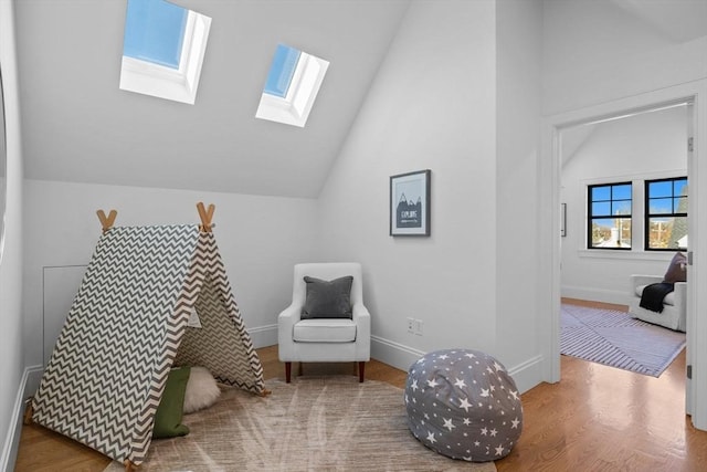 sitting room with hardwood / wood-style flooring and lofted ceiling with skylight