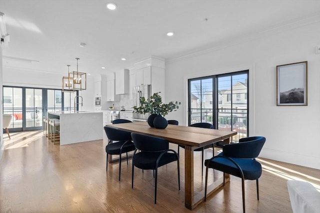 dining space featuring crown molding, light hardwood / wood-style floors, plenty of natural light, and sink