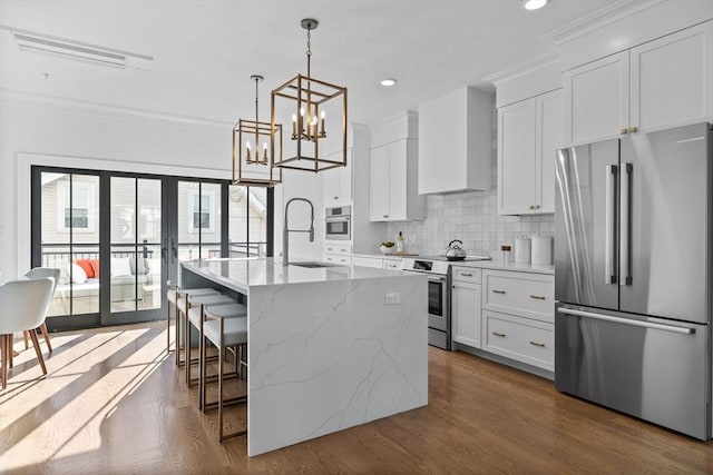 kitchen featuring white cabinetry, stainless steel appliances, a breakfast bar area, and an island with sink