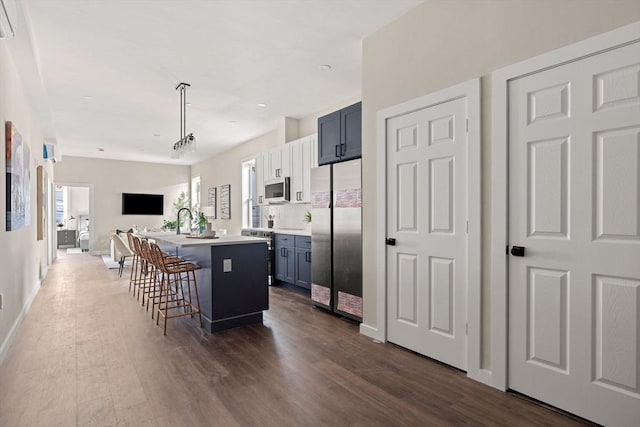 kitchen with dark wood finished floors, open floor plan, appliances with stainless steel finishes, and a kitchen breakfast bar