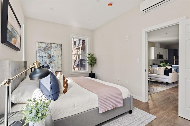 bedroom with an AC wall unit, wood finished floors, and baseboards