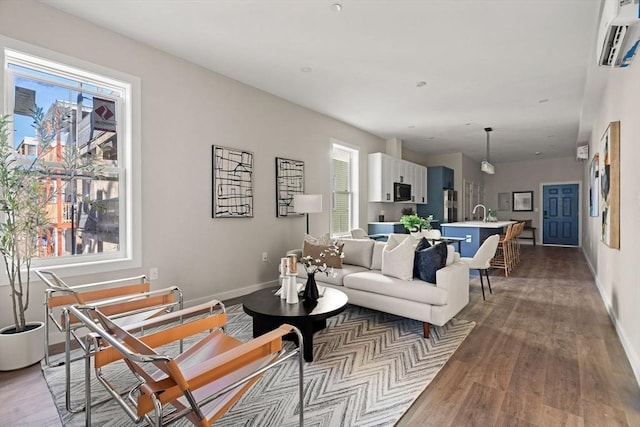 living room featuring an AC wall unit, light wood-style flooring, and baseboards