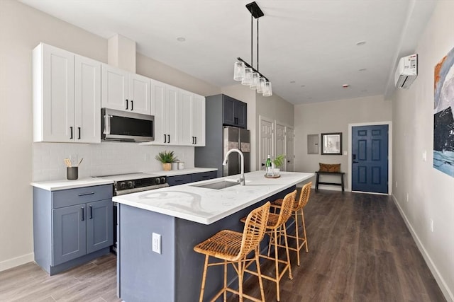 kitchen with an island with sink, a sink, appliances with stainless steel finishes, a breakfast bar area, and decorative backsplash