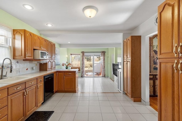 kitchen with dishwasher, white microwave, backsplash, light countertops, and a sink