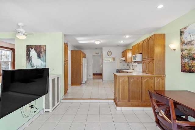 kitchen with white appliances, tasteful backsplash, a peninsula, light countertops, and light tile patterned flooring