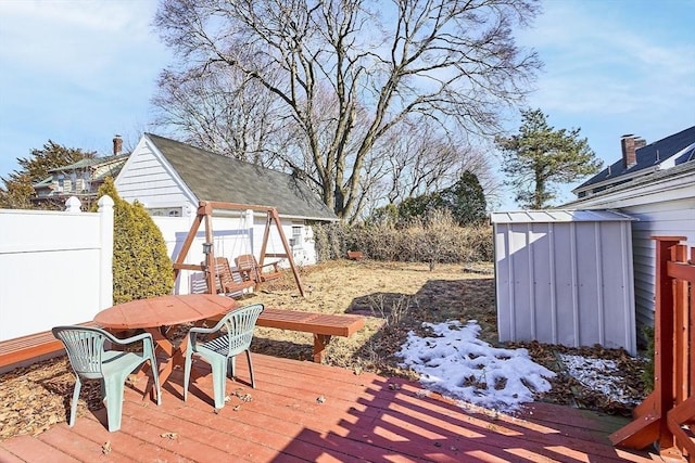 wooden deck with an outbuilding, outdoor dining area, fence, and a storage shed