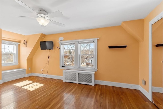 bonus room with a ceiling fan, baseboards, radiator heating unit, and wood finished floors