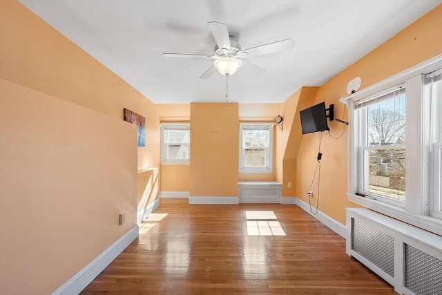 interior space featuring radiator, ceiling fan, baseboards, and wood finished floors