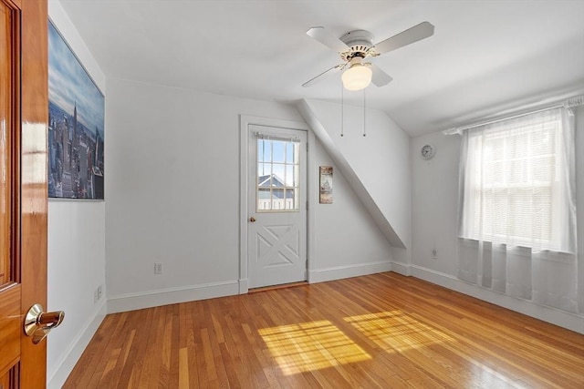 interior space with light wood-style floors, lofted ceiling, a healthy amount of sunlight, and baseboards