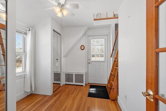 entryway with light wood-style floors, baseboards, radiator heating unit, and a ceiling fan