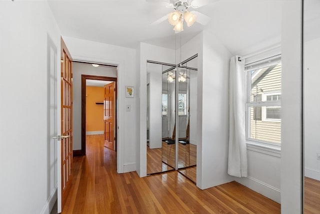 unfurnished bedroom featuring a closet, ceiling fan, baseboards, and wood finished floors