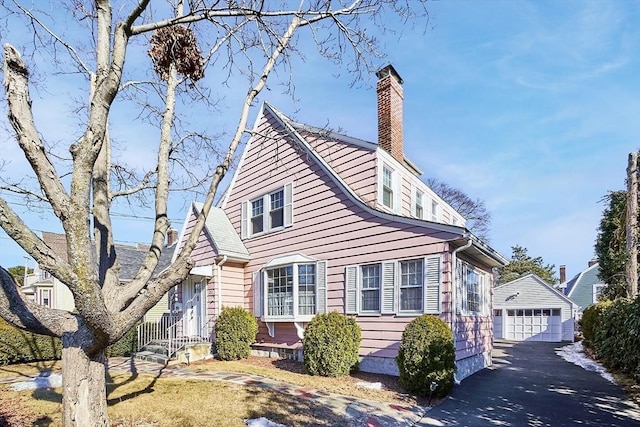 exterior space featuring a chimney, a detached garage, and an outbuilding