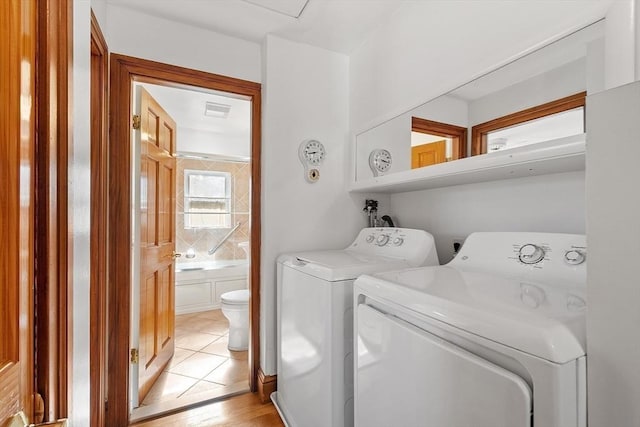 laundry area featuring washing machine and dryer, laundry area, light tile patterned flooring, and visible vents