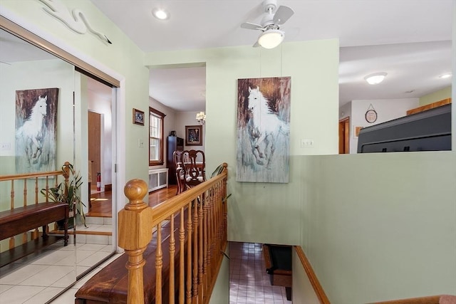 hallway featuring light tile patterned floors, recessed lighting, an inviting chandelier, and an upstairs landing