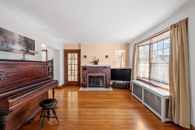 living area with baseboards, radiator heating unit, a fireplace, and light wood-style floors